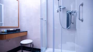 Un baño moderno con ducha de vidrio, inodoro blanco y tocador de madera con espejo.