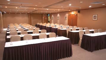 Un salón de conferencias con varias mesas y sillas, equipado con tarjetas de identificación y vasos de agua.