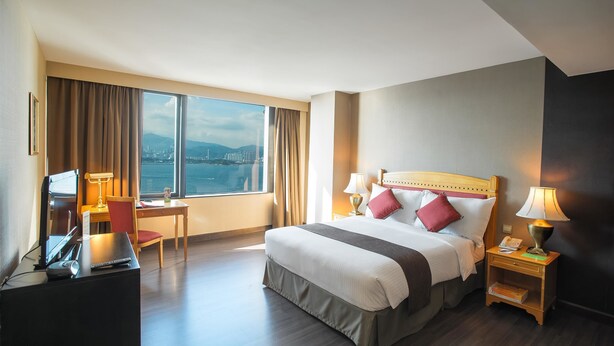 A hotel room with a large bed, a desk, and a view of the city.