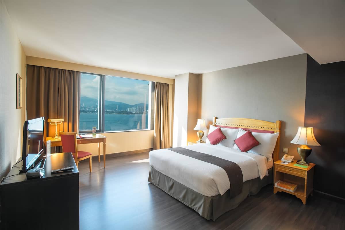 Habitación de hotel con una cama grande, un escritorio y vistas a la ciudad.