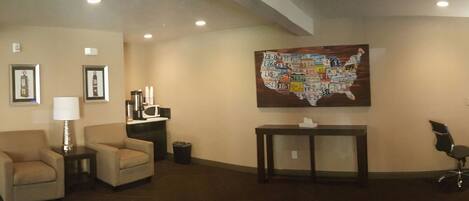 A lobby with a reception desk, two armchairs, a map on the wall, and a TV screen.