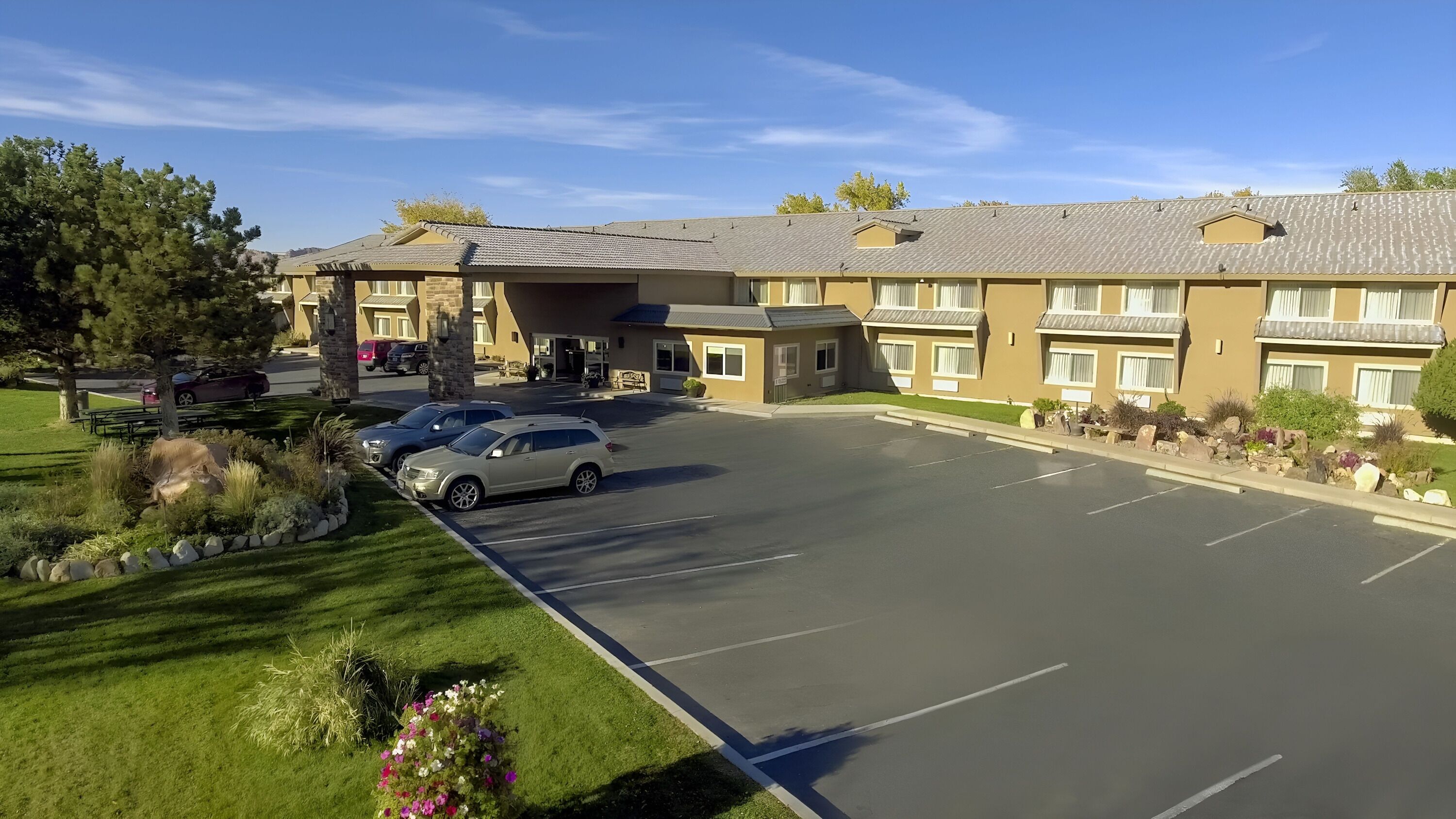 Et hotel med parkeringsplads, en overdækket gang og en anlagt have.
