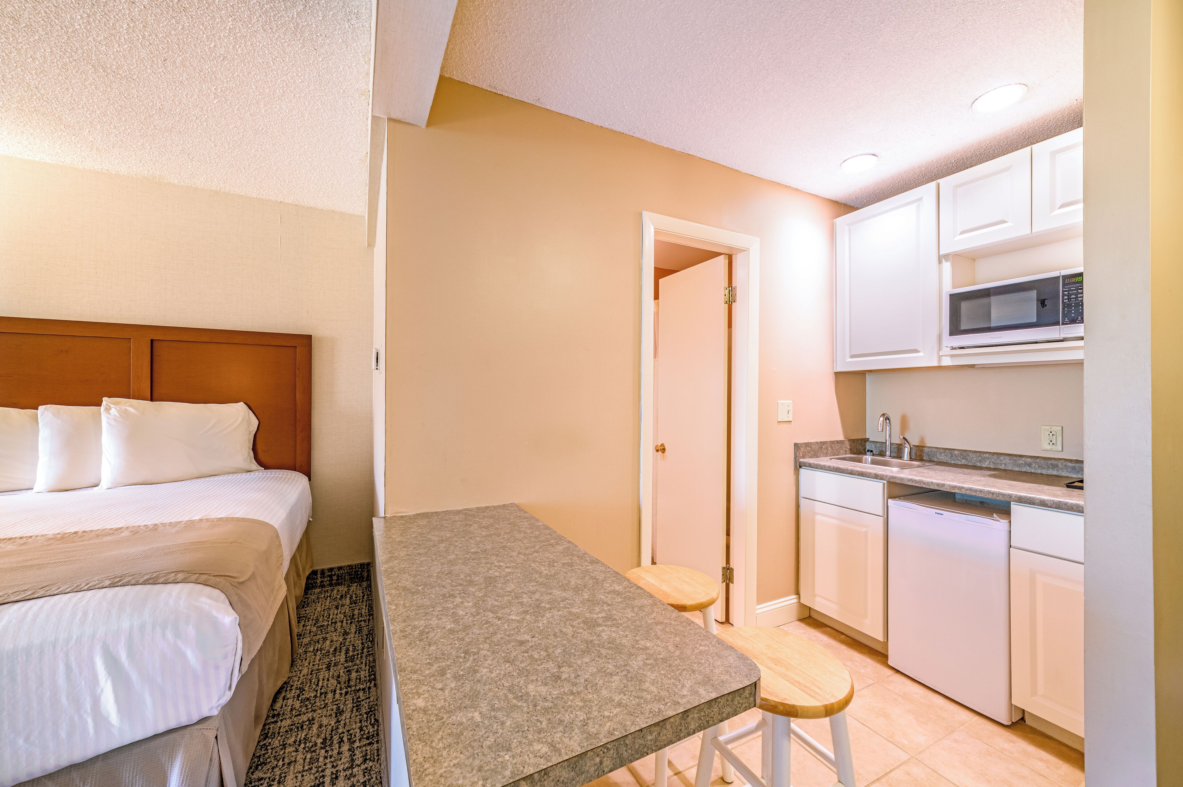 Une chambre d’hôtel comprenant un lit, une petite table, un coin cuisine avec un four à micro-ondes et un lave-vaisselle.