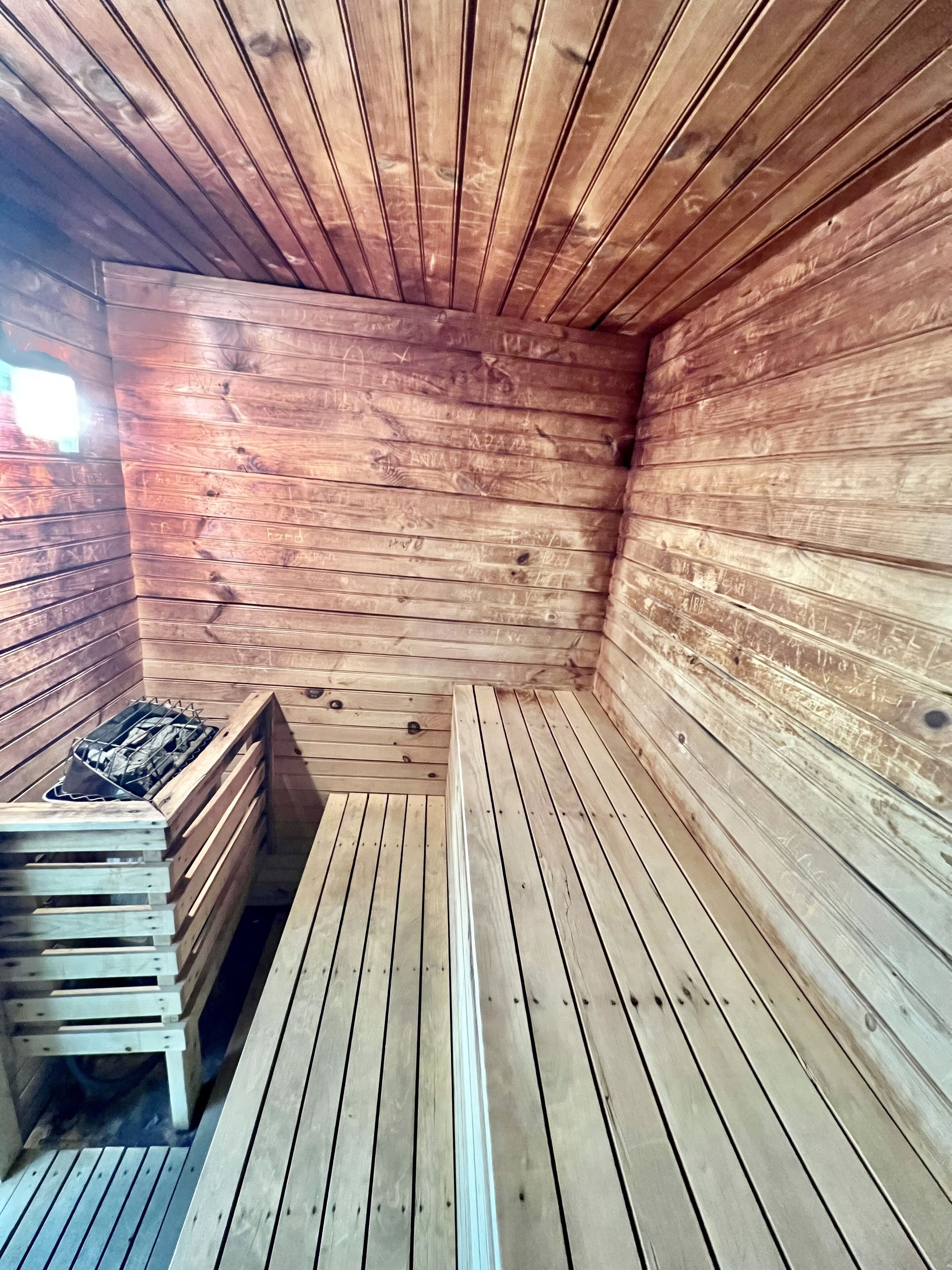 Un sauna avec des murs et des bancs en bois.