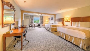 Una camera d'albergo con due letti, una scrivania, una sedia, una lampada e un grande specchio.