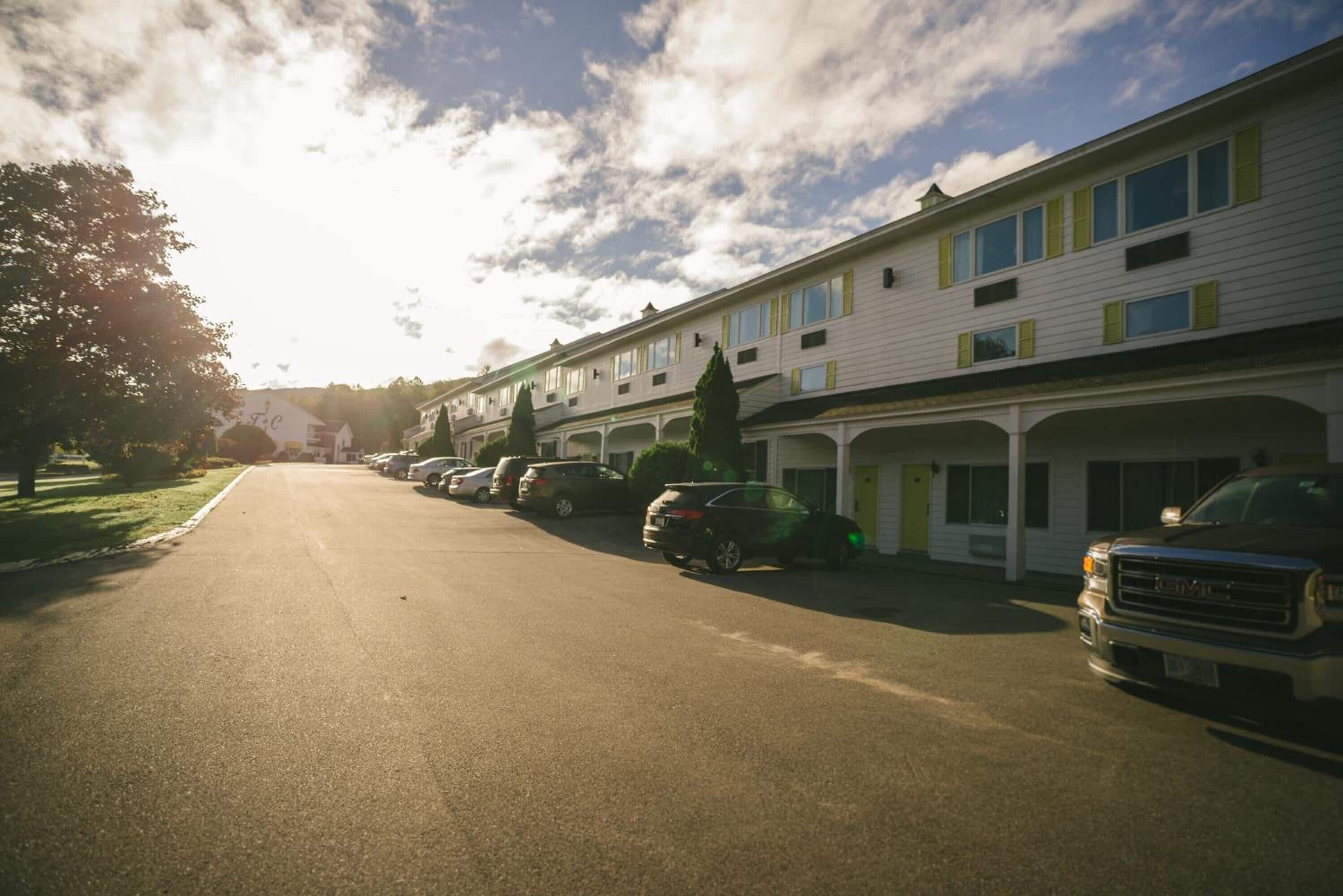 Række af byhuse med tilhørende garager, parkerede biler og en klar himmel.