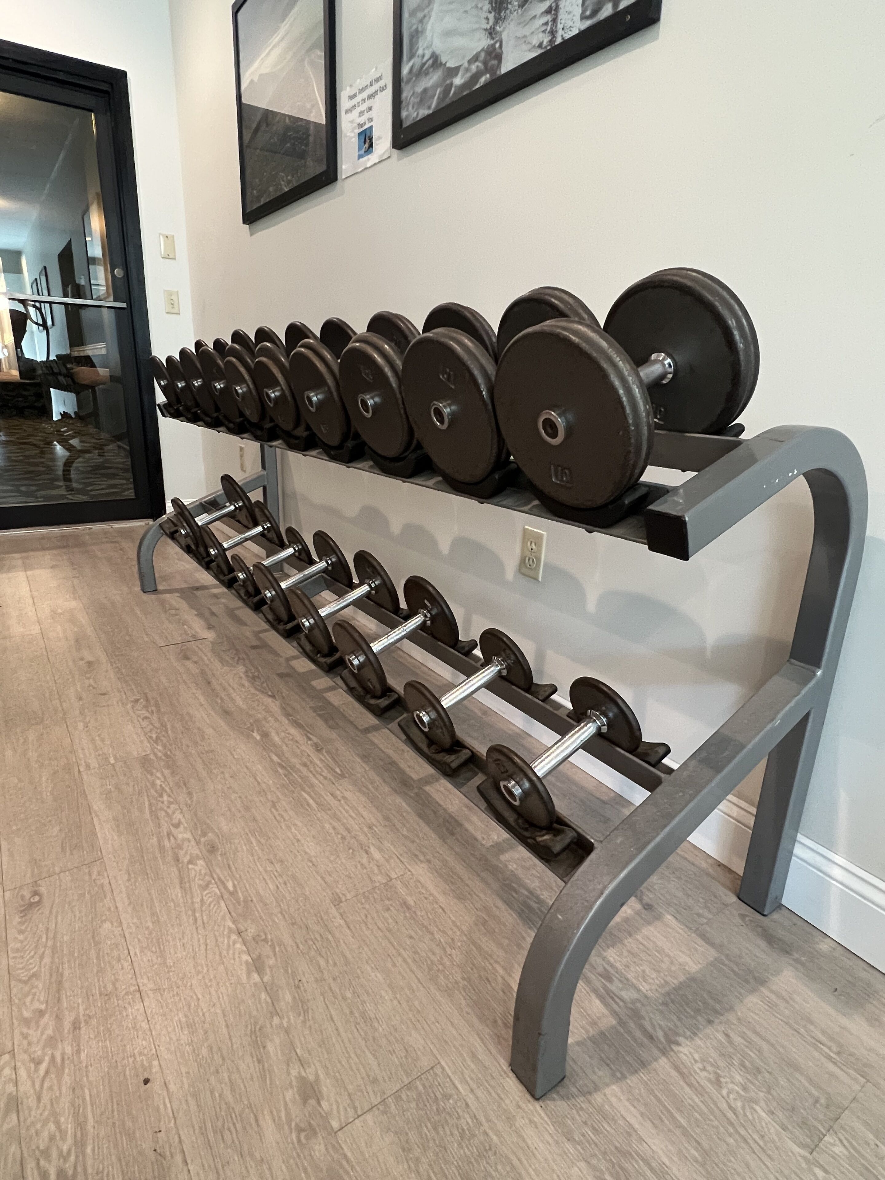 Une salle de sport équipée de matériel de musculation, notamment des haltères et des barres, disposés sur un porte-haltères.
