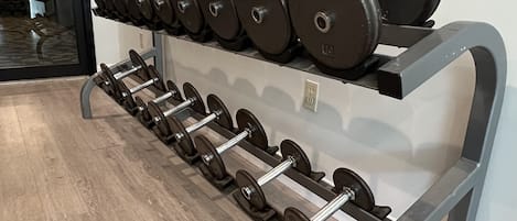 Une salle de sport équipée de matériel de musculation, notamment des haltères et des barres, disposés sur un porte-haltères.