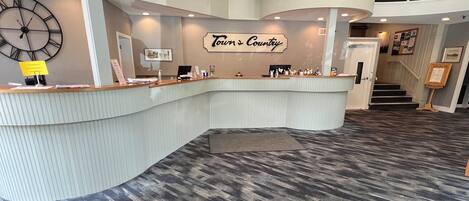 A reception area with a curved counter, a clock, and a sign reading 'Town & Country.'