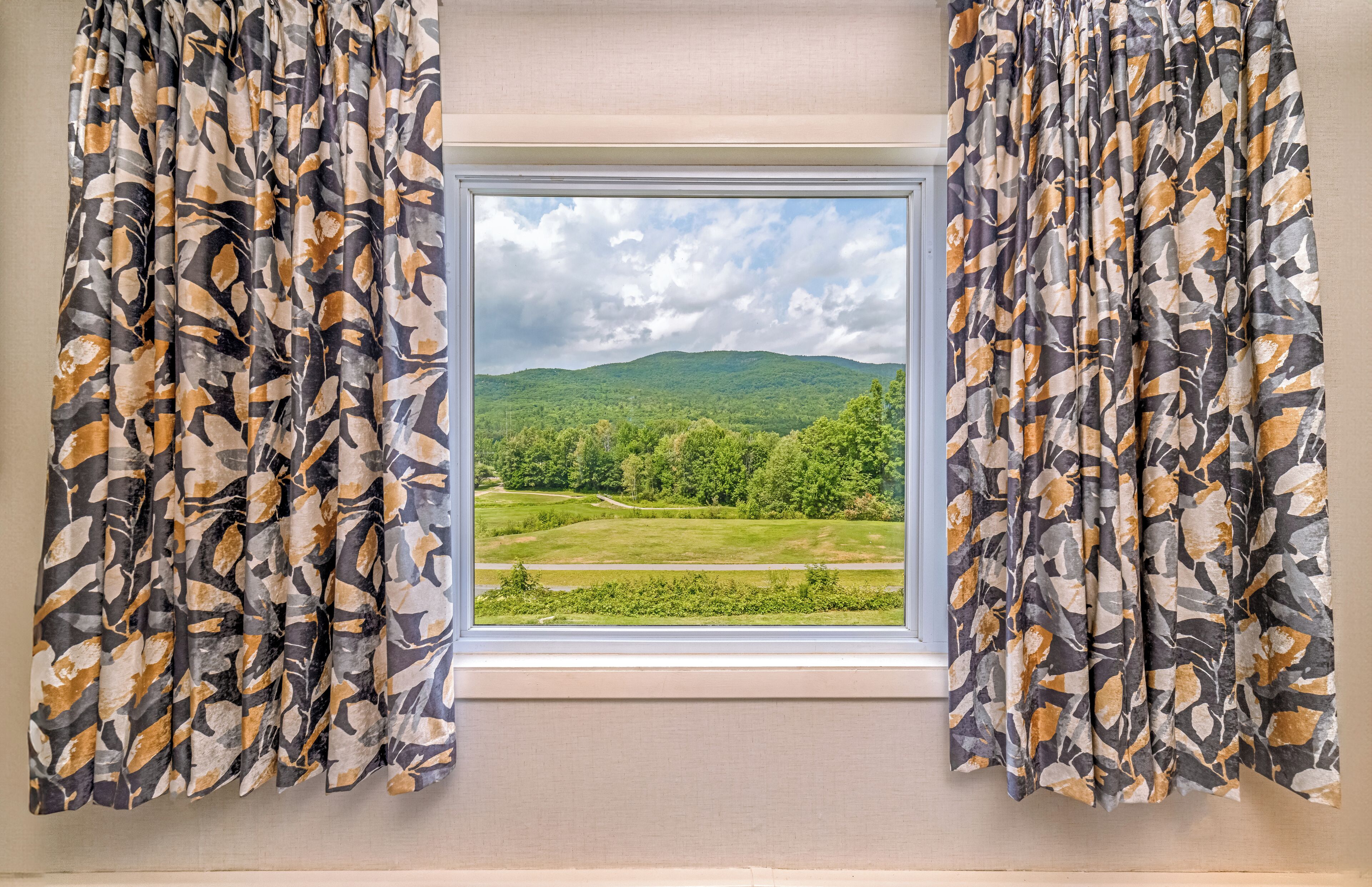 A window with a view of a green landscape and hills.
