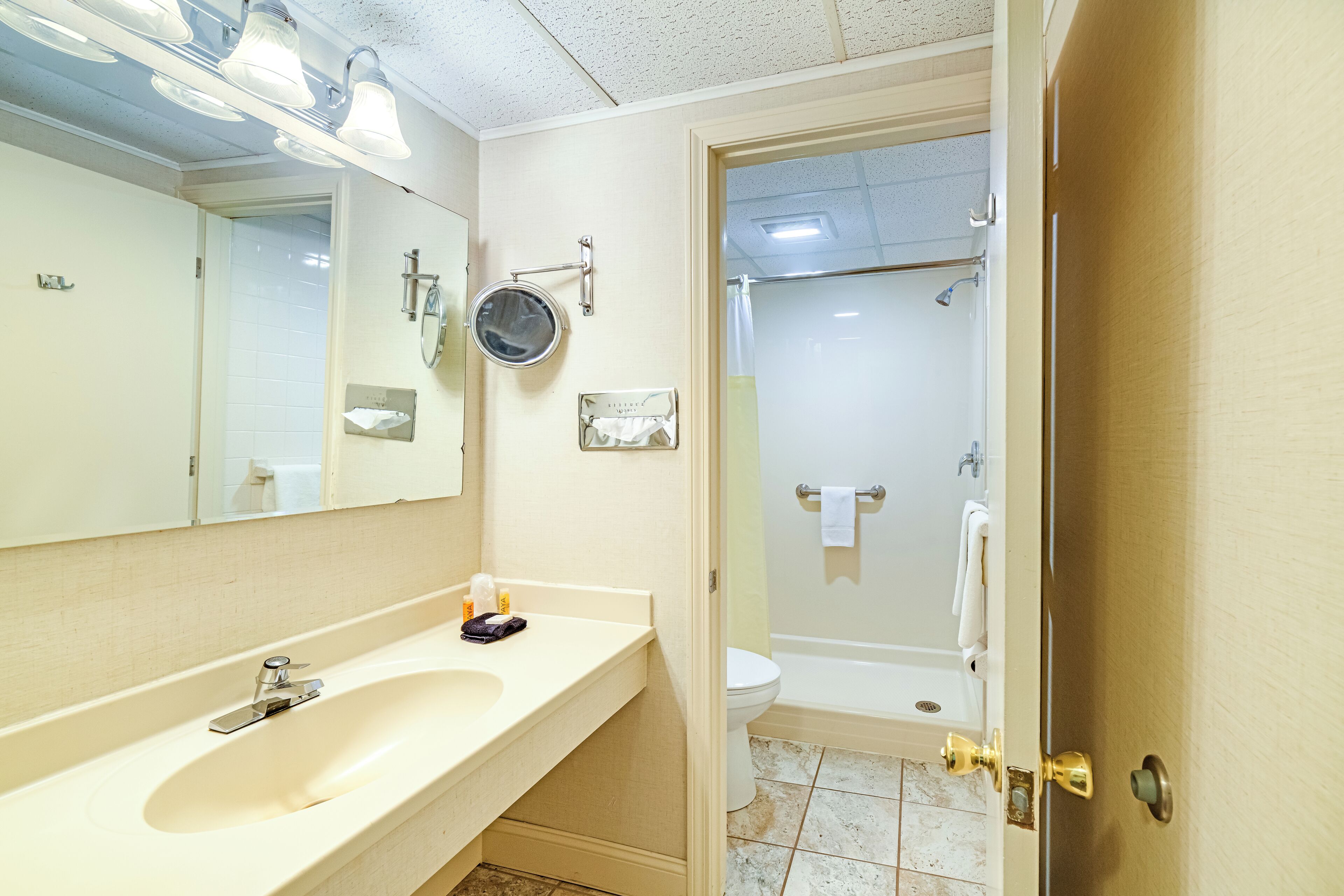 A bathroom with a sink, mirror, towel rack, and a shower area.