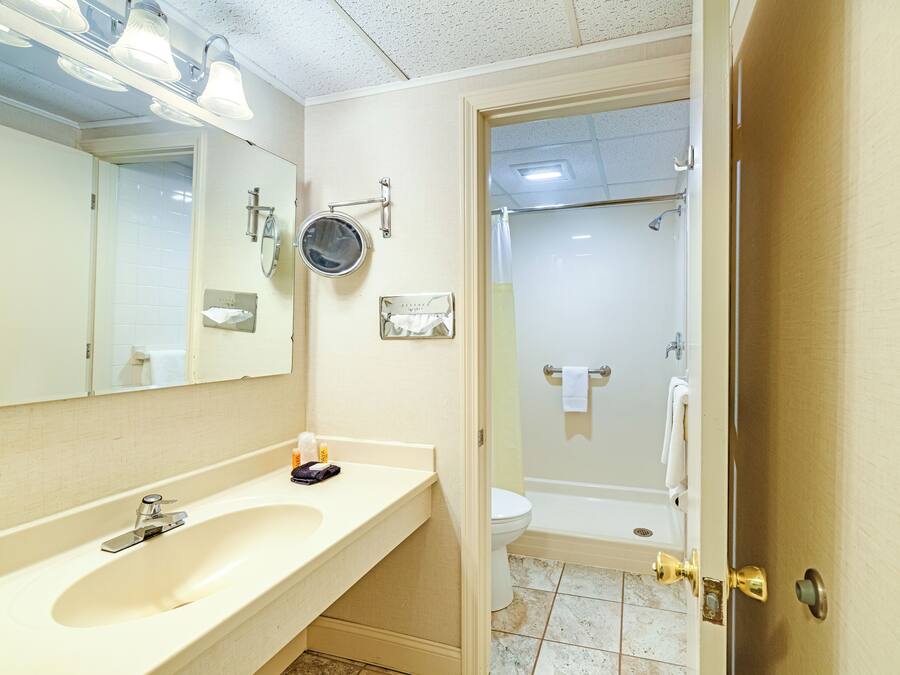 A bathroom with a sink, mirror, towel rack, and a shower area.