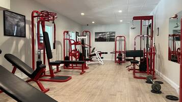 Un gimnasio con varias máquinas de ejercicio, bancos y pesas.
