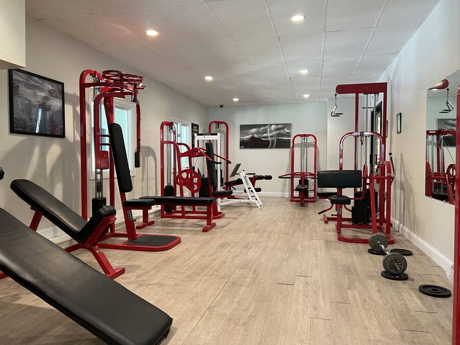 Un gimnasio con varias máquinas de ejercicio, bancos y pesas.