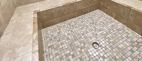 A tiled shower area with a drain in the center.