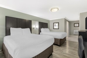 Habitación de hotel con dos camas, un escritorio y una silla.