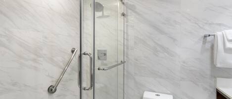 A modern bathroom with a glass shower enclosure, a white toilet, and a towel rack.