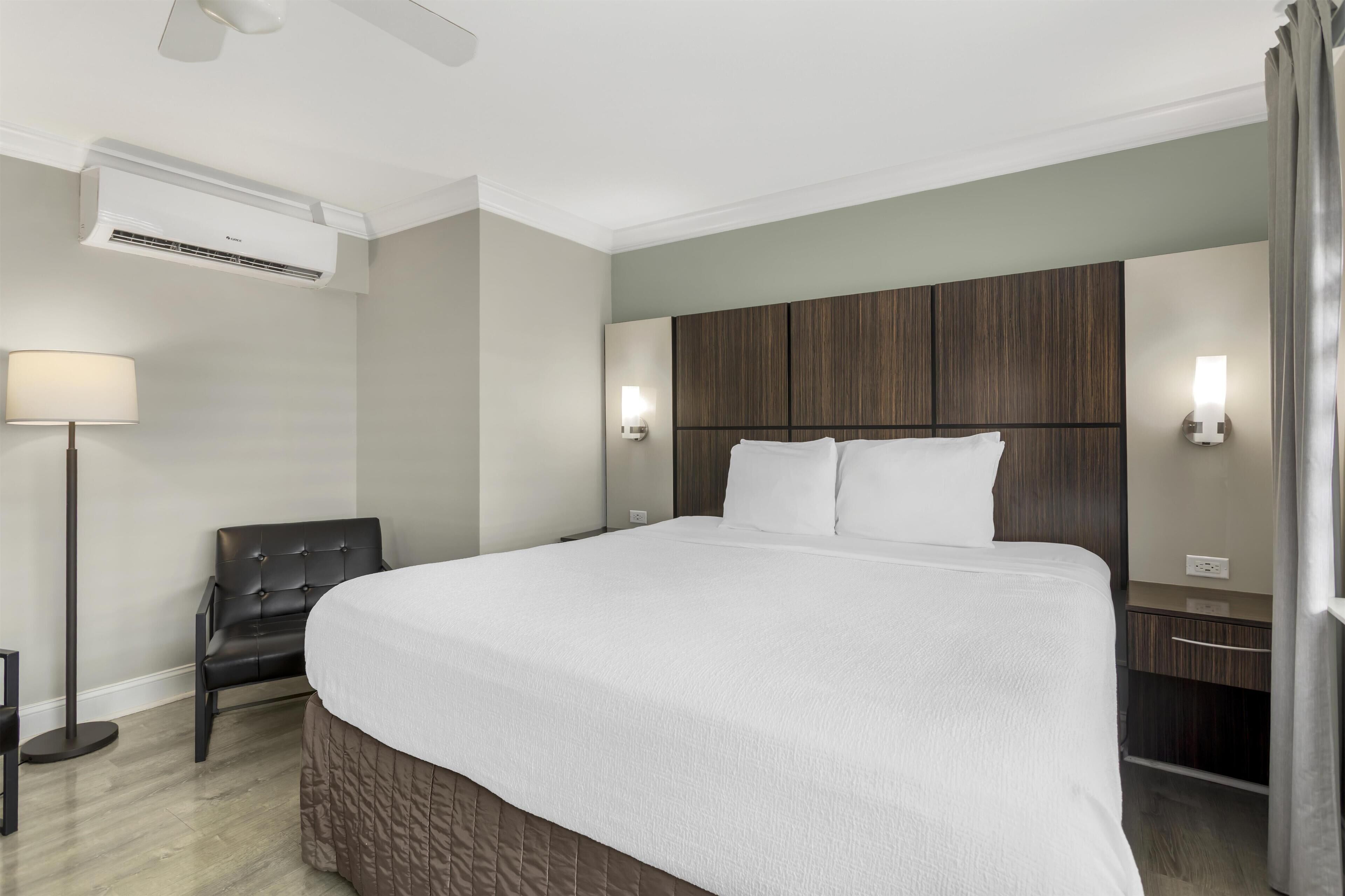 Une chambre d’hôtel moderne équipée d’un grand lit, d’un bureau, d’une chaise et d’un lampadaire.