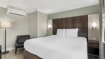 Een moderne hotelkamer met een groot bed, een bureau, een stoel en een staande lamp.