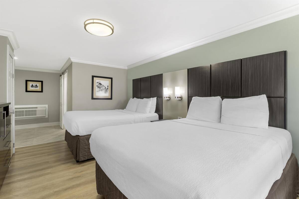 A hotel room with two beds, a large mirror, and a small table.