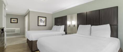 Una habitación de hotel con dos camas, un espejo grande y una mesita.