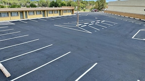 Un parking avec des places délimitées et, au fond, un bâtiment à la façade jaune.