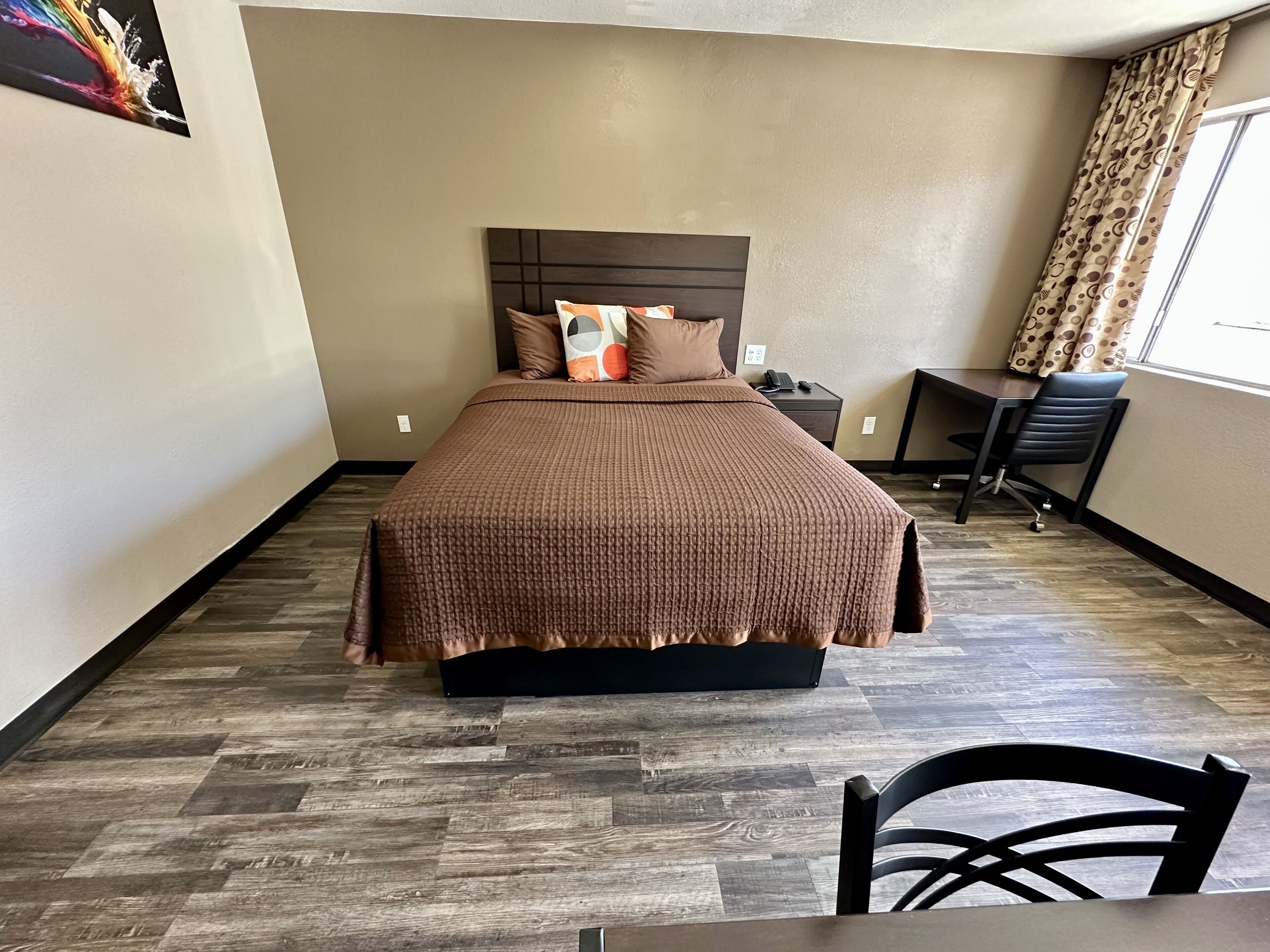 A hotel room with a large bed, a desk, and a chair.