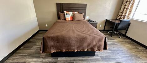 A hotel room with a large bed, a desk, and a chair.