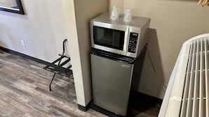 Une petite cuisine équipée d’un four à micro-ondes, d’un petit réfrigérateur et d’une prise électrique au mur.