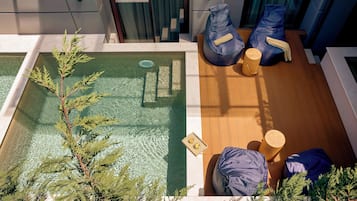 A rooftop pool area with a small pool, seating, and a wooden deck.