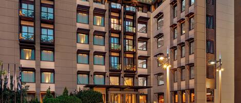Et moderne hotel med flere etager, med altaner, store vinduer og en godt oplyst indgang.