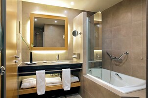 Un baño moderno con ducha de vidrio, tocador con espejo y dos toallas sobre la encimera.