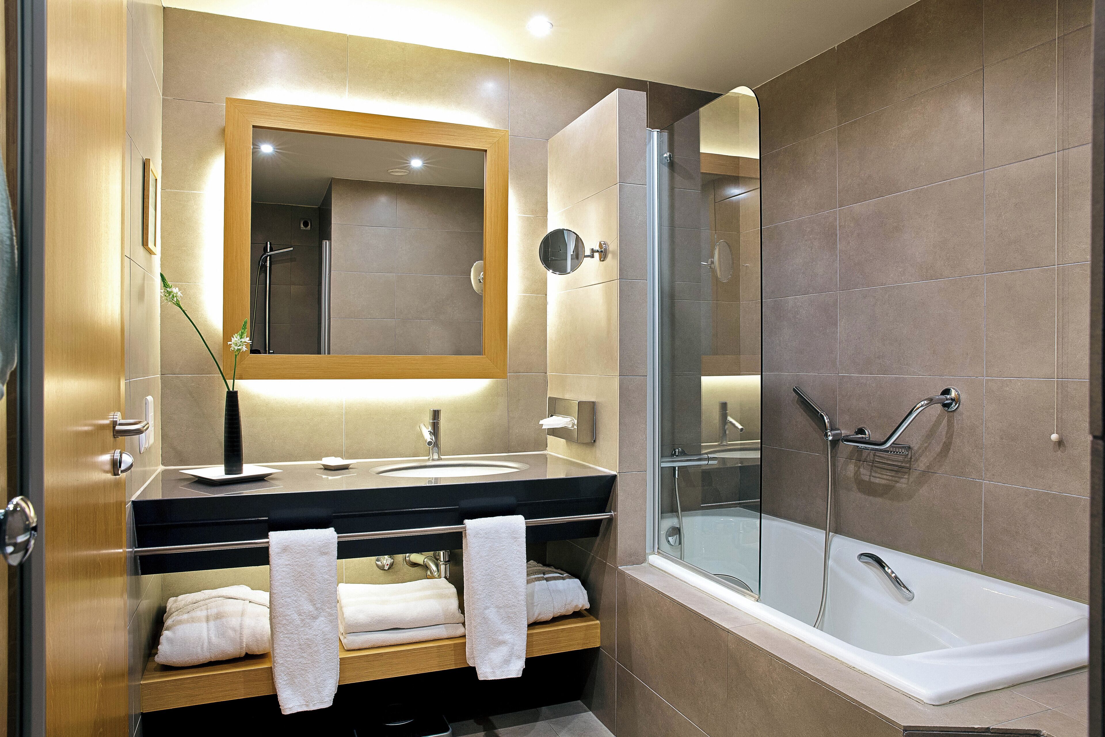A modern bathroom with a glass shower enclosure, a double sink vanity, and a large mirror.