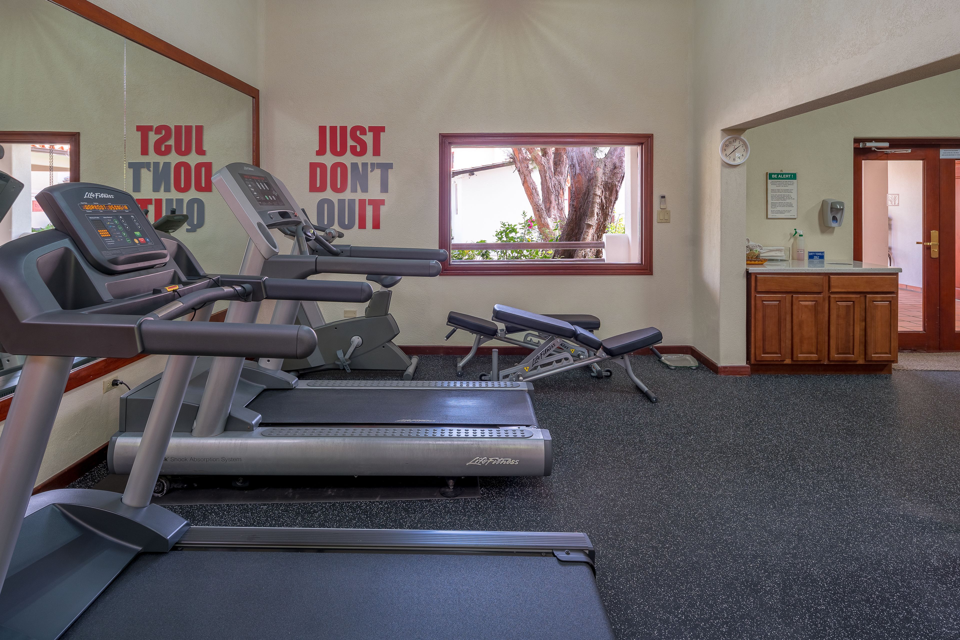 A gym with treadmills, a bench, and a wall with motivational quotes.