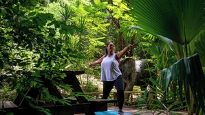 Une personne fait de l’exercice sur une plateforme en bois, entourée d’une végétation luxuriante.