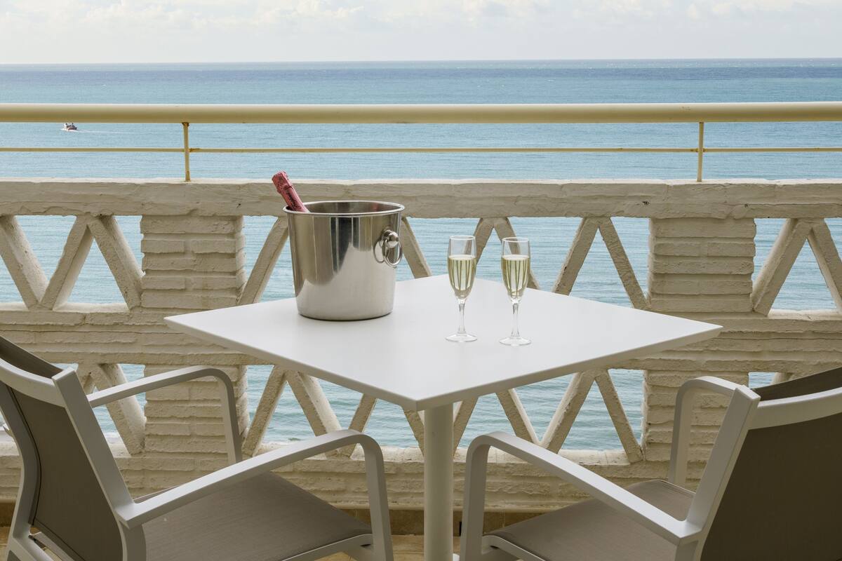A table with a champagne bucket and glasses, overlooking the sea.