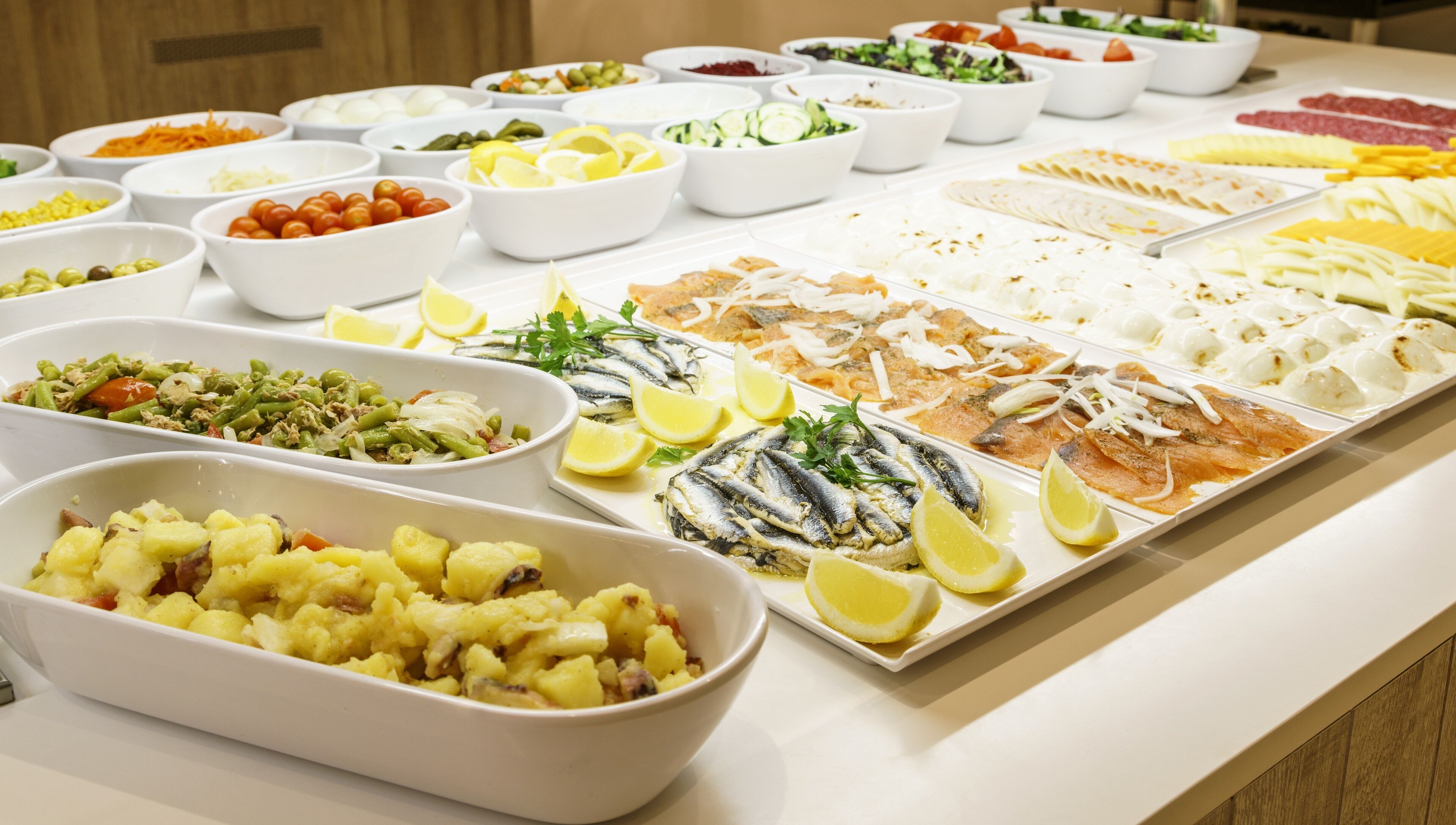 A buffet with various dishes including fish, salads, and potatoes.