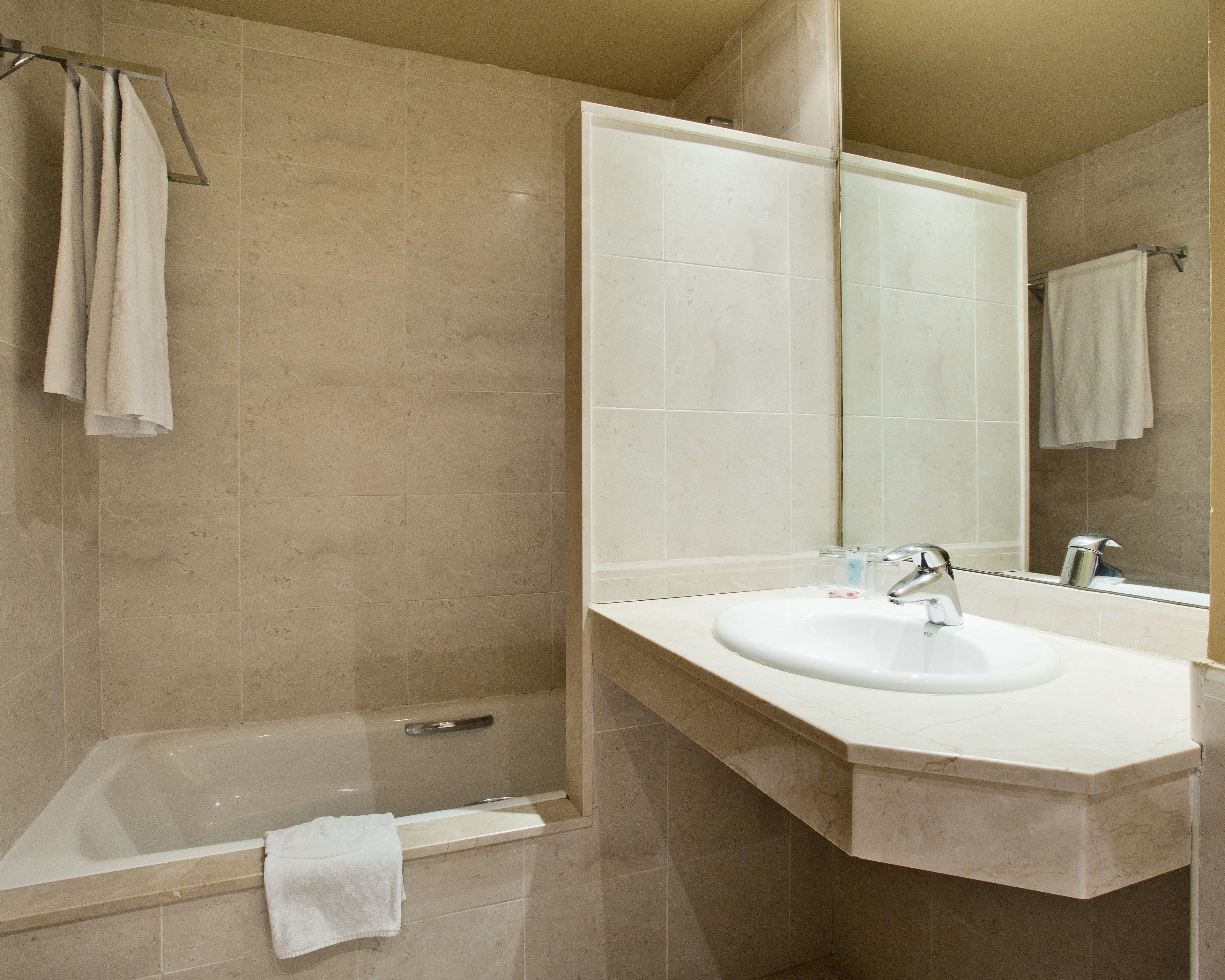 Un baño con bañera, lavamanos y un espejo grande.