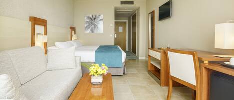 A hotel room with a bed, a sofa, a desk, and a TV.