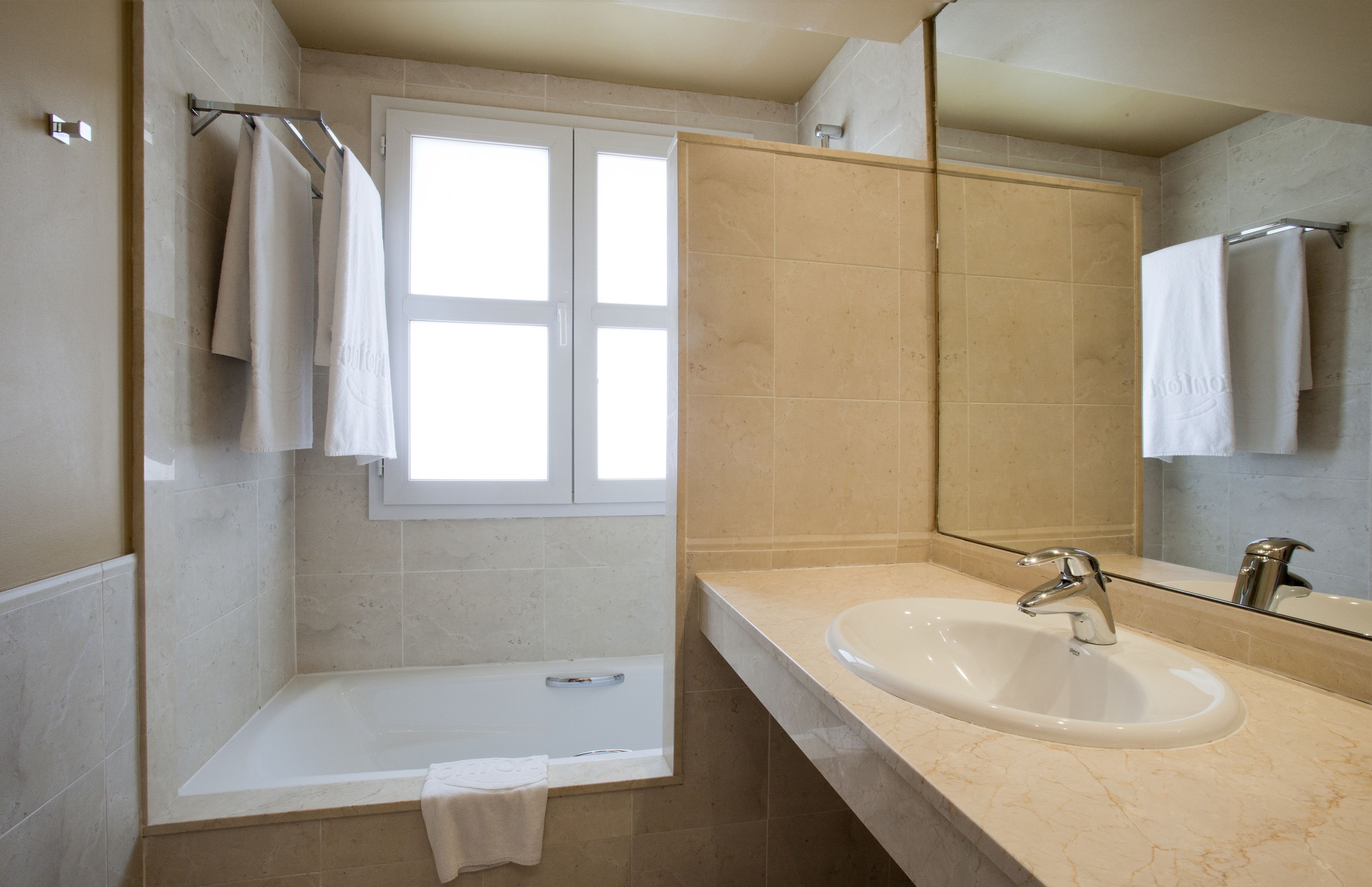 A modern bathroom with a bathtub, a sink, and a large mirror.