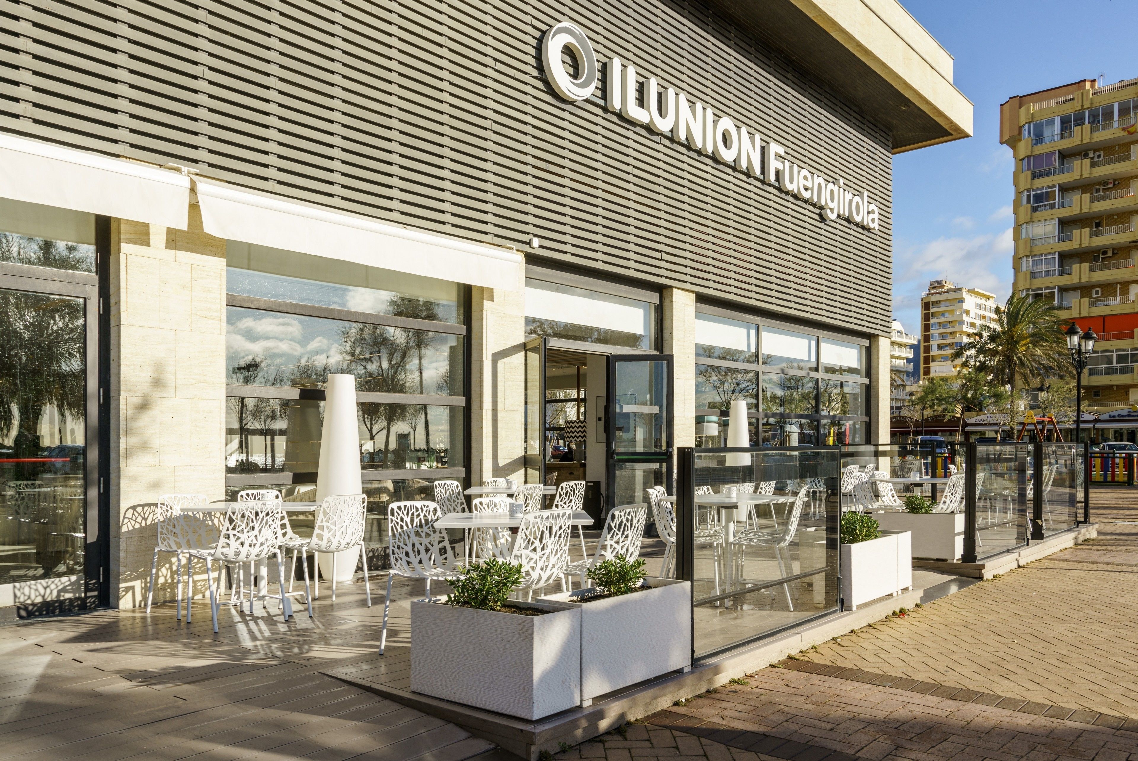 Edificio ILUNION Fuengirola con asientos exteriores y ventanas grandes.