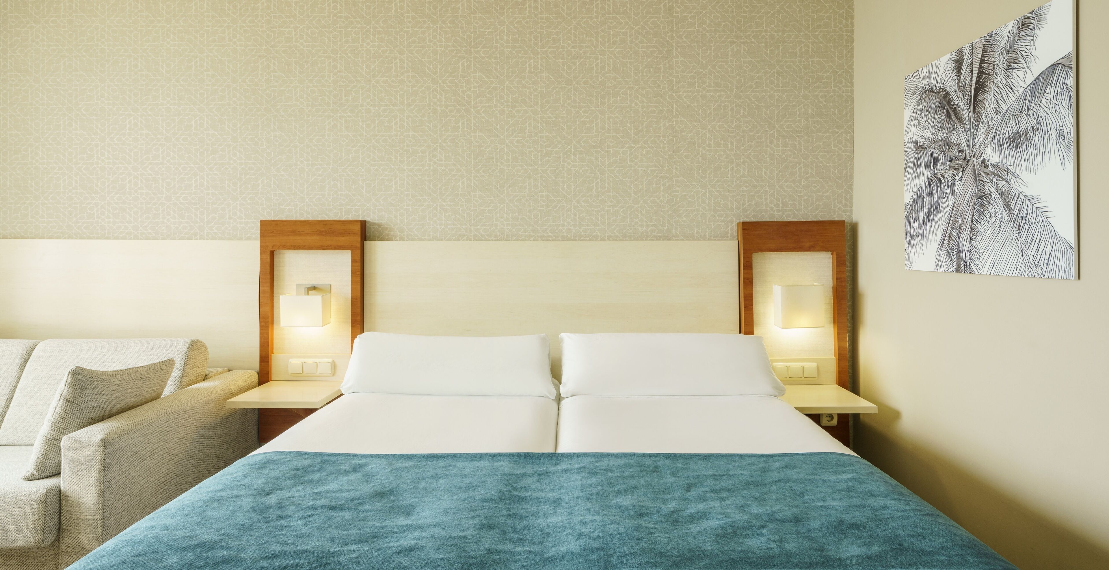 A hotel room with a bed, two bedside tables, a nightstand, a lamp, and a wall-mounted picture.