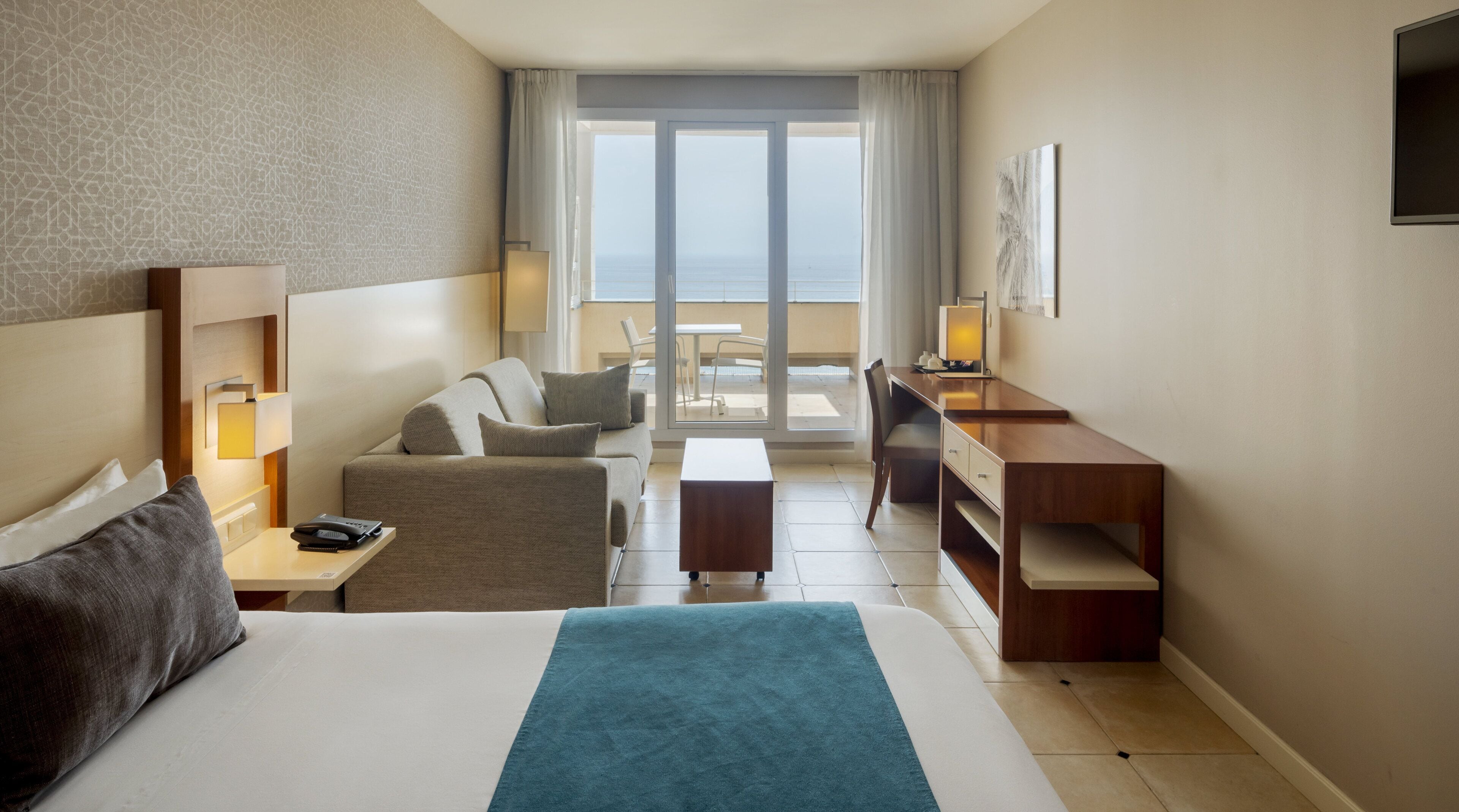 Une chambre d’hôtel avec un grand lit, un bureau, une chaise et un balcon avec vue.