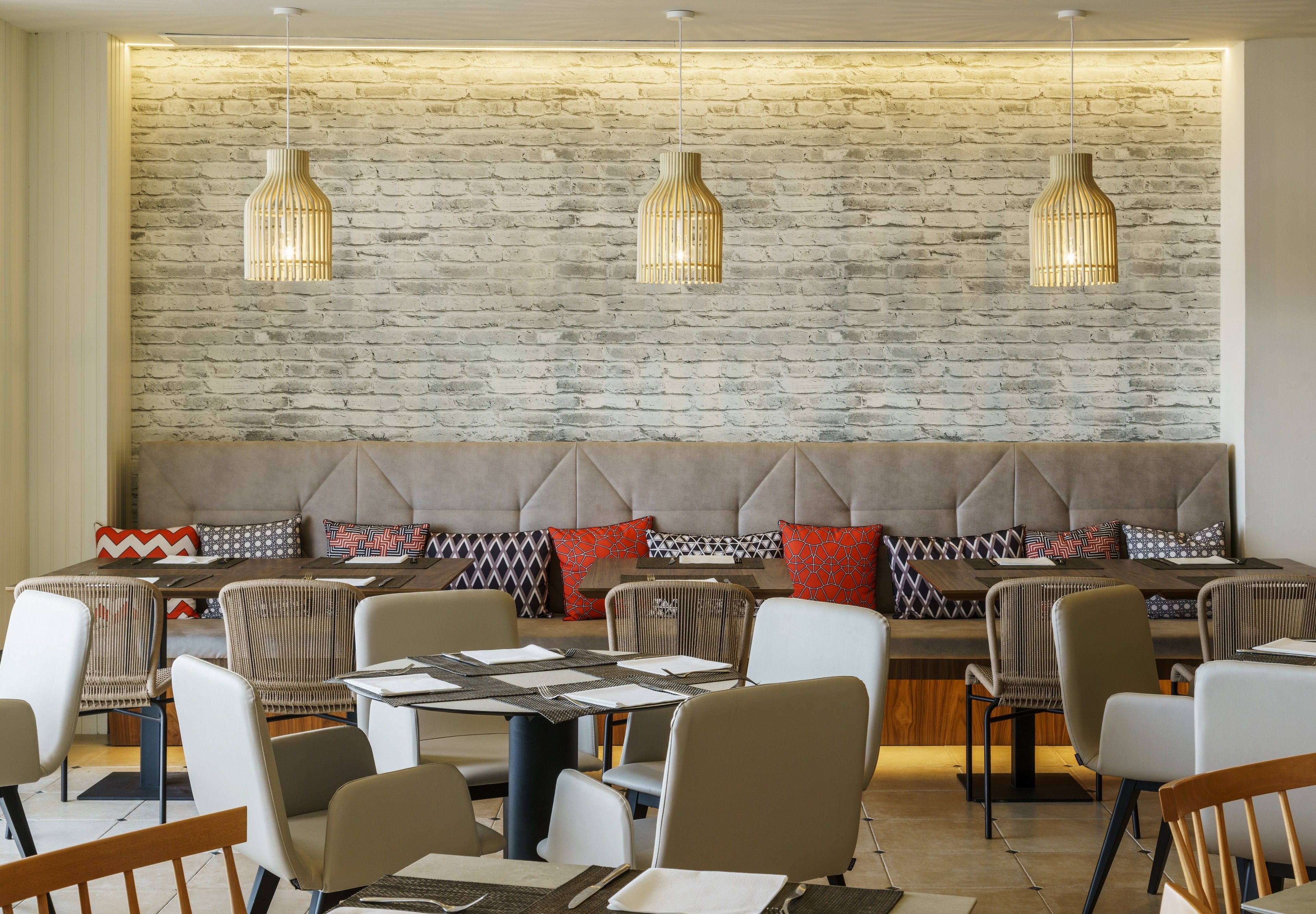 Un restaurante con pared de ladrillo, asientos acolchados e iluminación colgante.