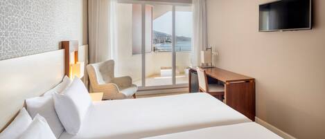 A hotel room with a large bed, a desk, a chair, and a TV.