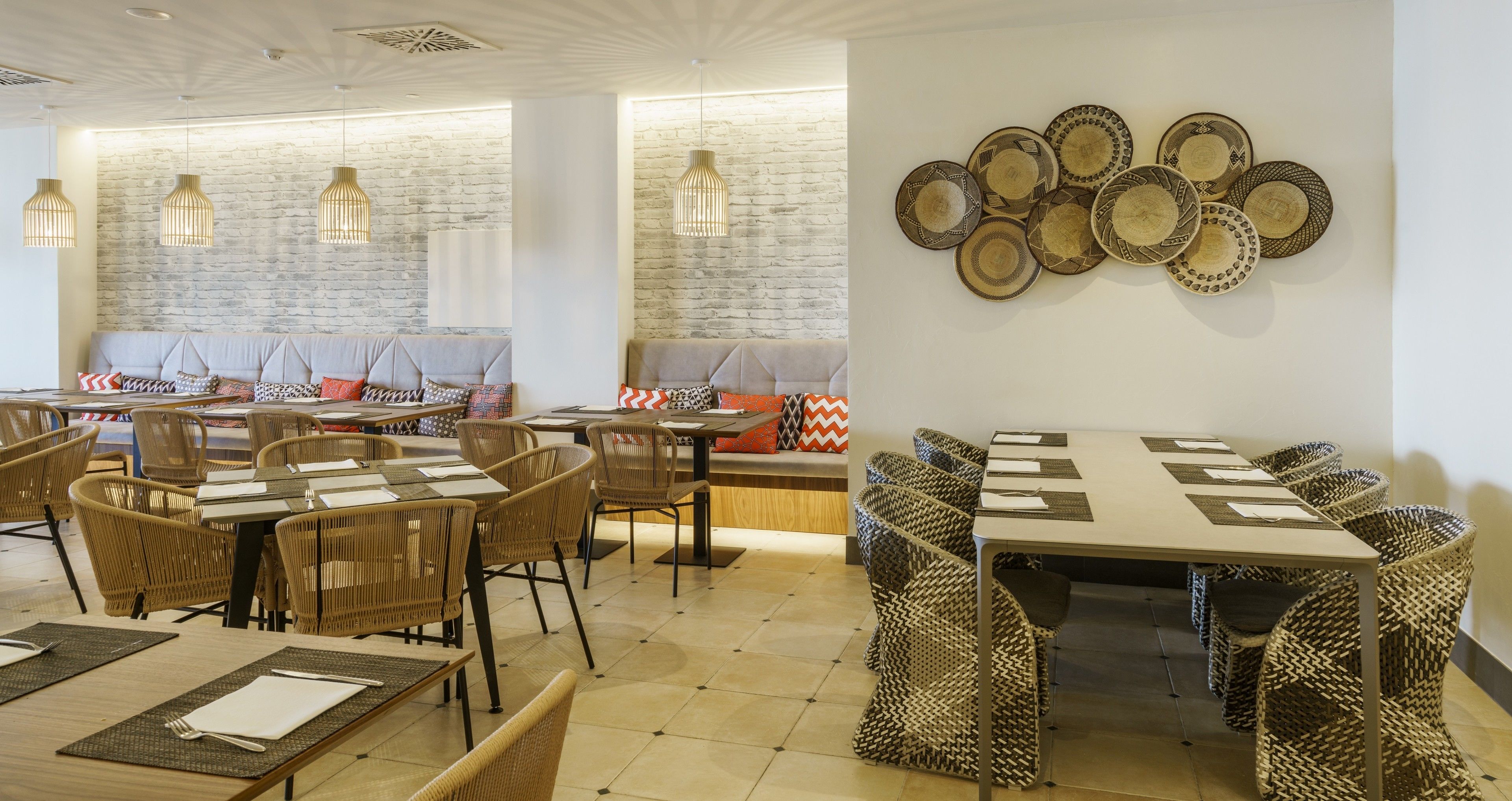 A restaurant with wicker furniture, a brick wall, and a wall of decorative plates.