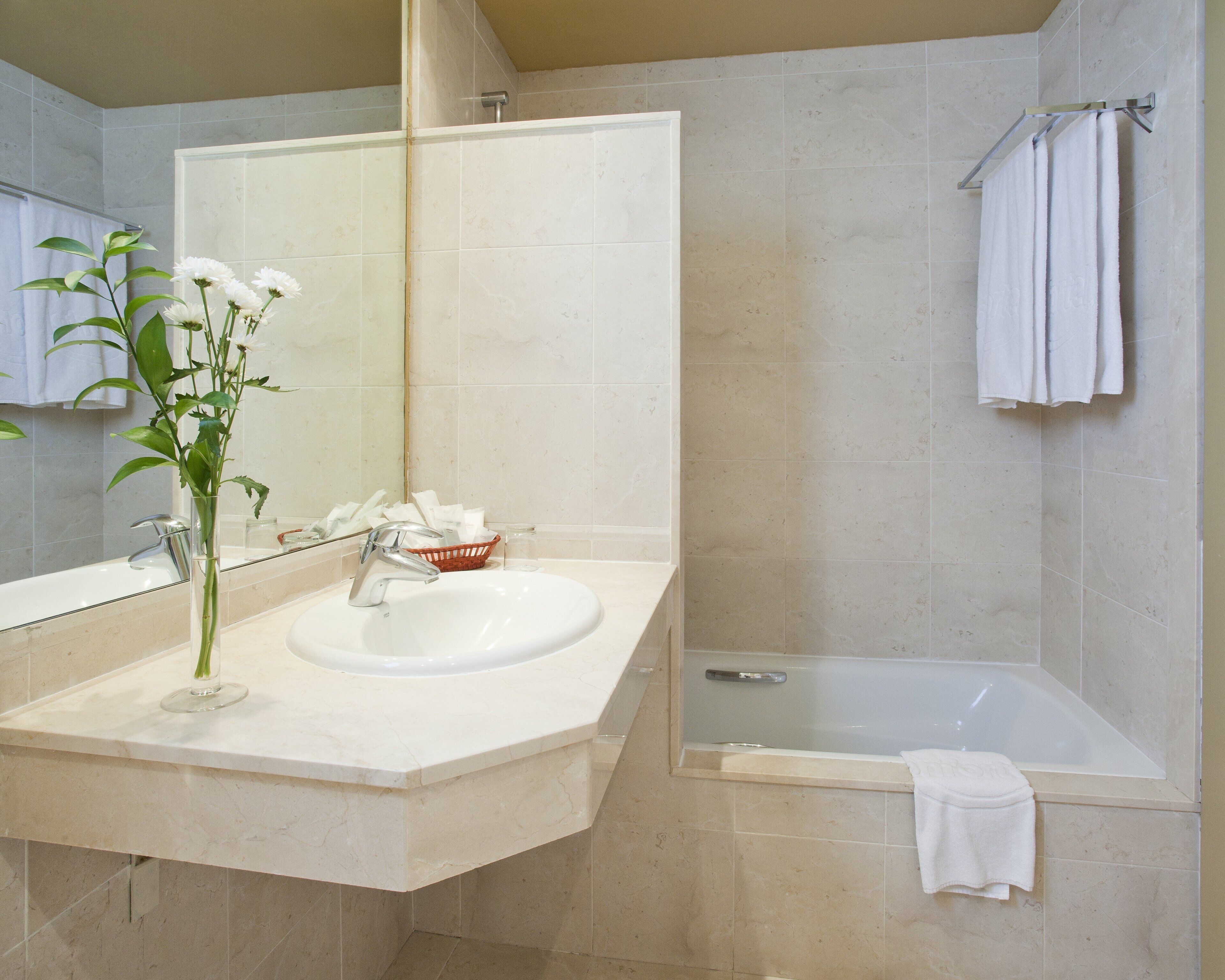 A bathroom with a sink, mirror, and bathtub.