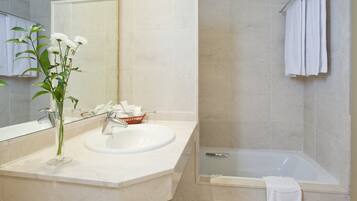 A bathroom with a sink, mirror, and bathtub.
