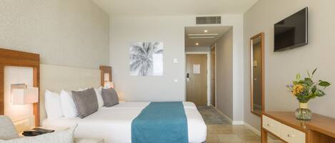 A hotel room with a bed, a desk, a chair, a TV, and a painting on the wall.