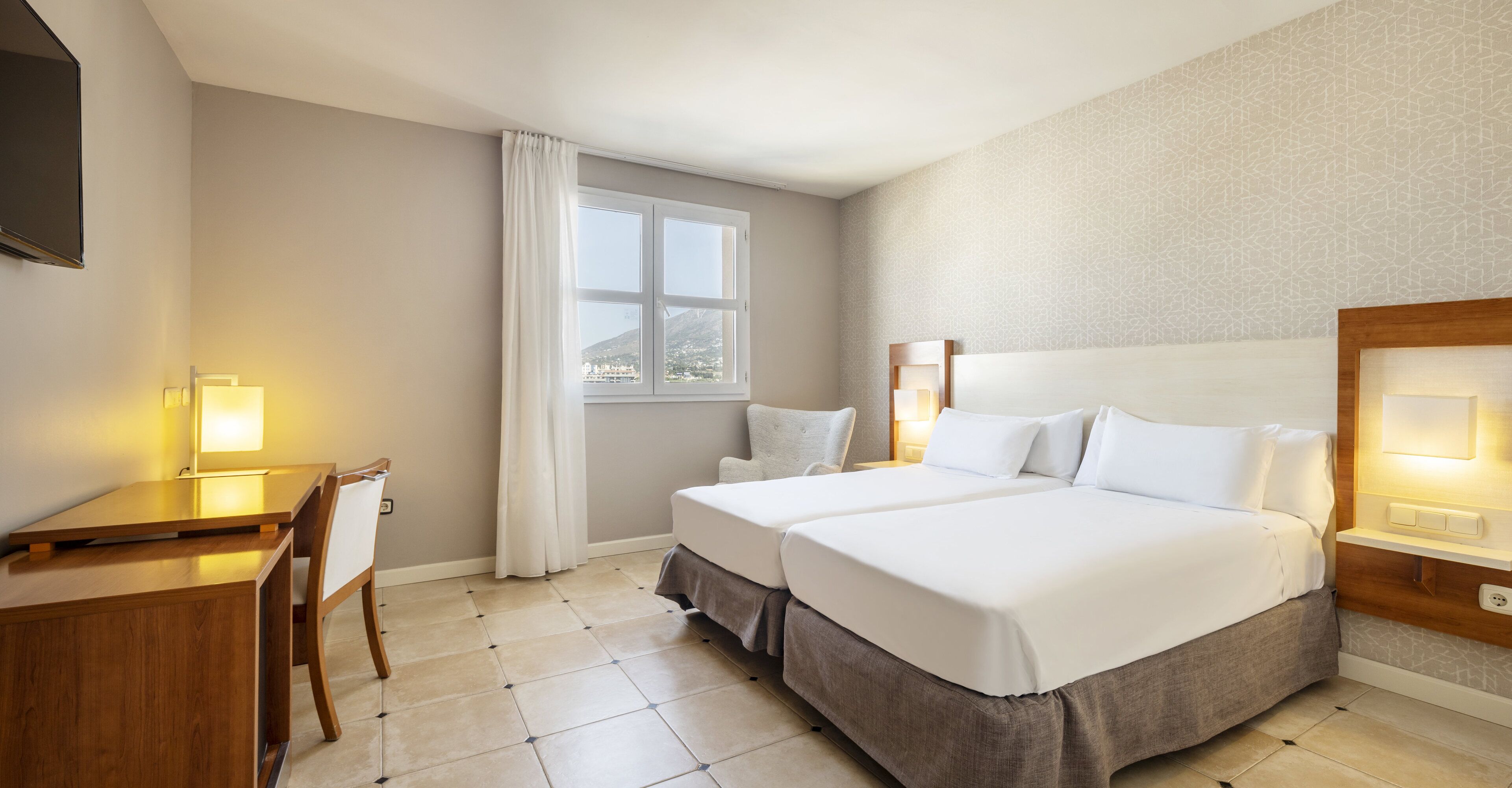 Habitación de hotel con dos camas, un escritorio y una silla.